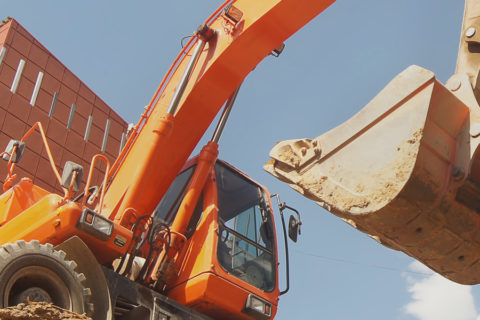 Pelleteuse orange creusant un chantier de construction